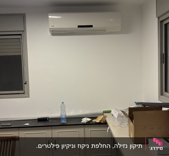 חדר עם מזגן מותקן על הקיר וארונות מטבח